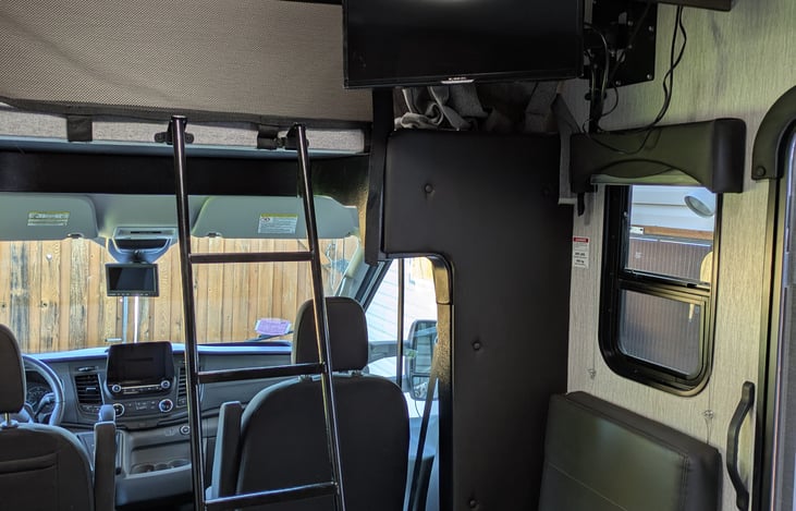 TV latches to the wall when in motion and can swivel facing the bed above the cab or to the bed in the back or angled right at the table .