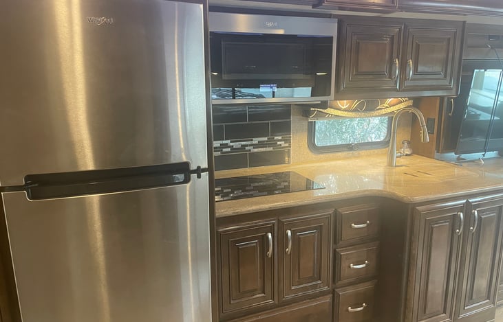 Kitchen has residential sized refrigerator and freezer, electric stove tops, convection microwave and sink