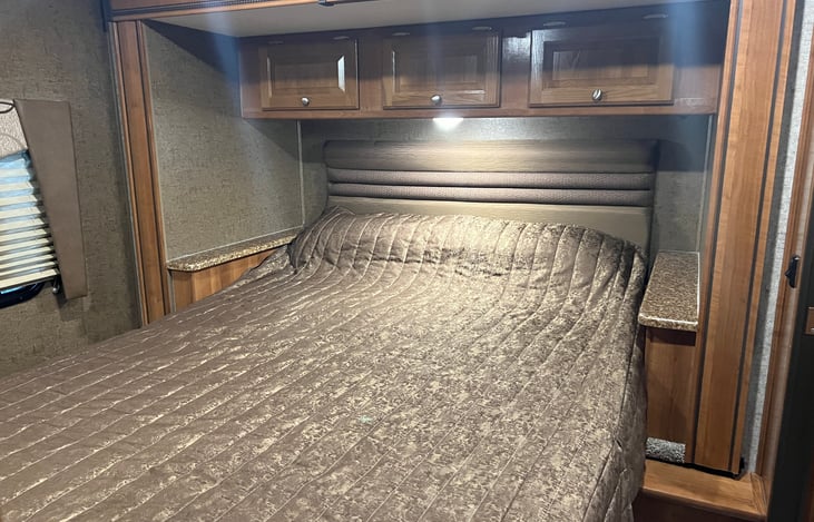 Queen-sized bed with storage above. Areas on each side with charging plugs for phones. Bedroom has a door that closes for privacy and it's own entrance to the bathroom.