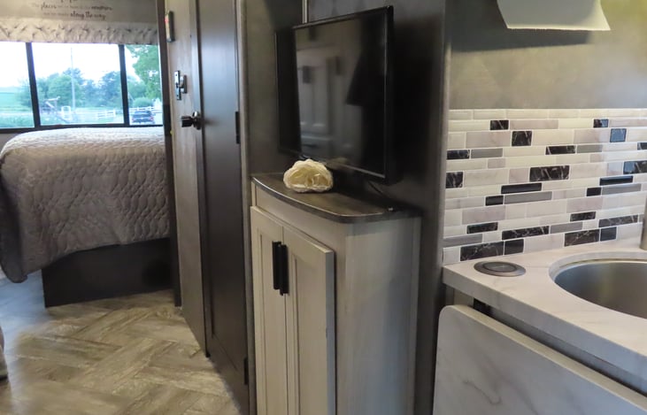 Hallway to master bedroom with bathroom door on right and bunk beds on left. Privacy curtains separates bunks from main cabin and a wooden door for master bedroom.