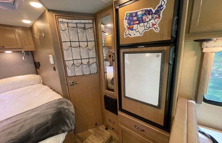 Fridge and freezer with doors closed. Small Wardrobe closet with mirror. Bathroom door.