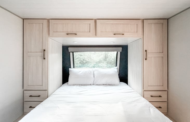 Queen bed, large window, and plenty of storage in primary bedroom.