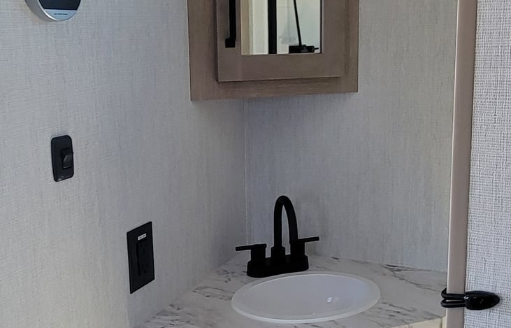 bathroom sink and water heater thermostat in upper left