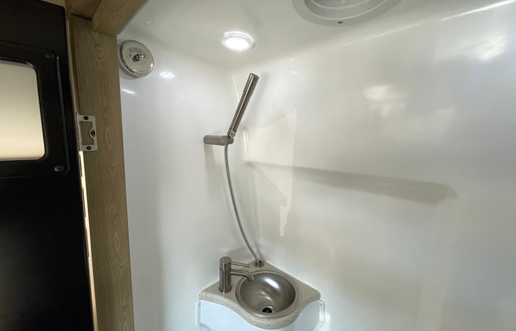 Stainless steel sink and shower wand are durable and aesthetically pleasing.