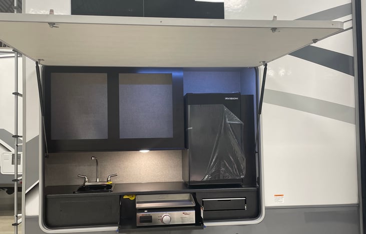 Outdoor kitchenette with full sink, grill, chopping/prep station, fridge and storage space