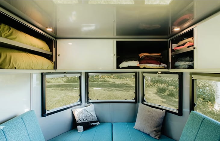 Mid to back view showing open storage bed, and huge windows in back. All windows have black-out blinds for sleeping and they also have screens and can open wide for plenty of fresh air.