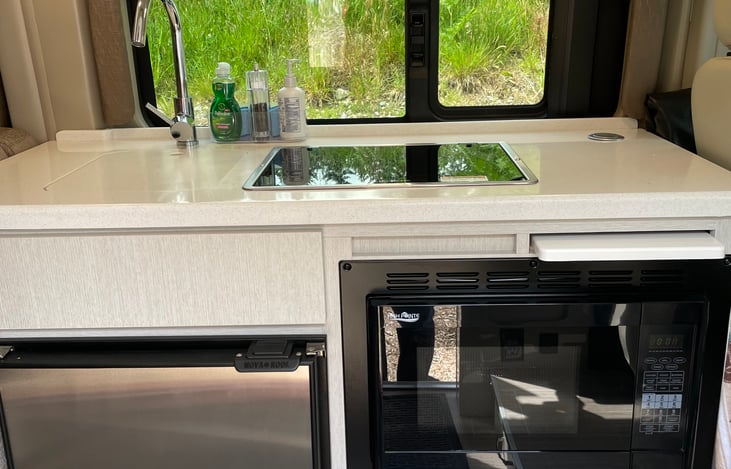 The galley -- sink (covered by cutting board), stovetop, refrigerator, microwave/convection oven