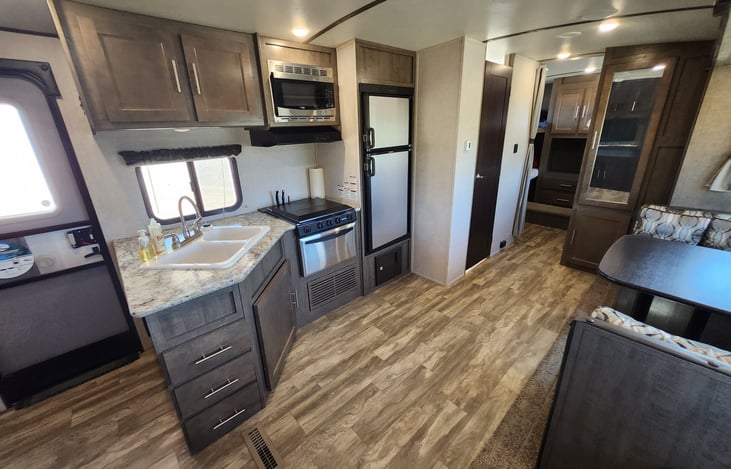 A look at the spacious living room, dinette, and kitchen with plenty of storage from the front door from the couch and slideout.