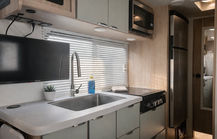 Fully stocked kitchen with 2 burner stove, microwave, refrigerator, toaster, and coffee pot