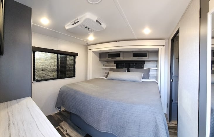 Entering from the second outside door at the rear of the RV into the king room. Plenty of room on both sides of the bed to comfortably get in and out of bed, and lots of storage space overhead.