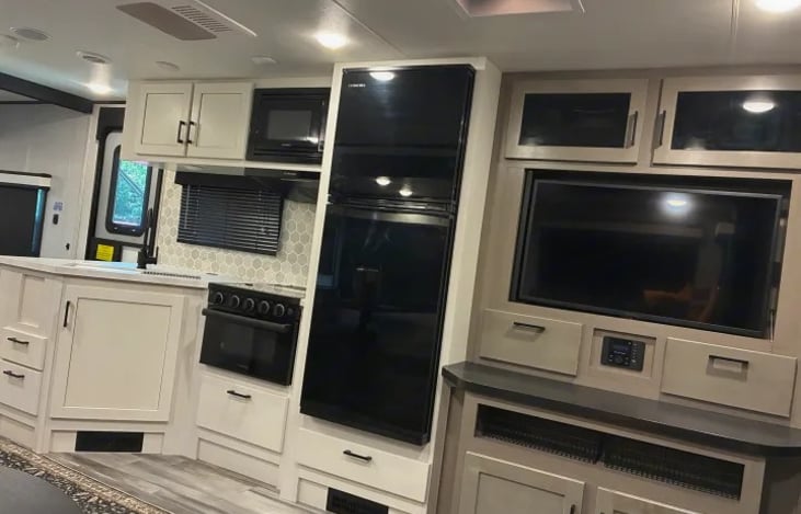 The premium entertainment center features a clear LED Smart TV on a swing-out mount, paired with integrated Bluetooth indoor/outdoor speakers.