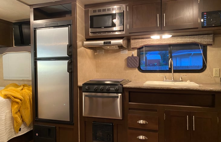 Fully stocked kitchen with 3 burner propane stove, oven, refrigerator/freezer and microwave.