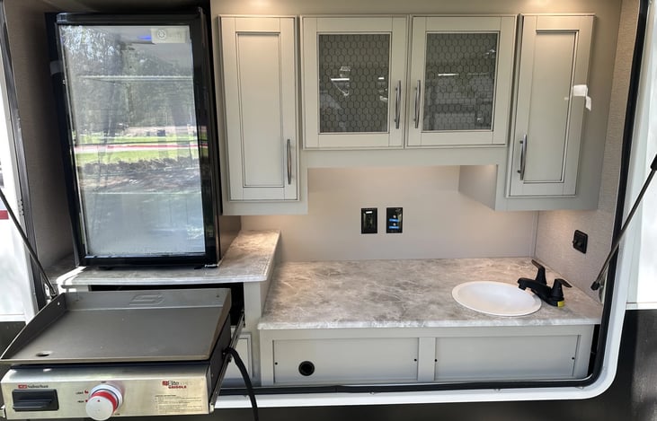 Outdoor kitchen w/griddle, fridge and sink.