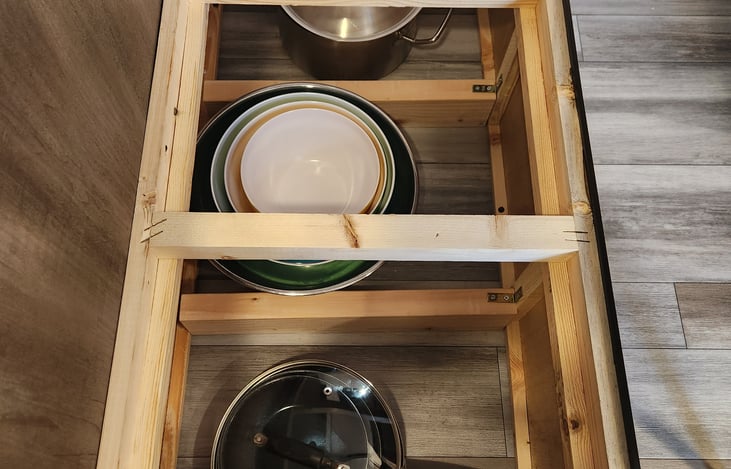 Frying pans, mixing bowls, soup pots  under the dinette seating.