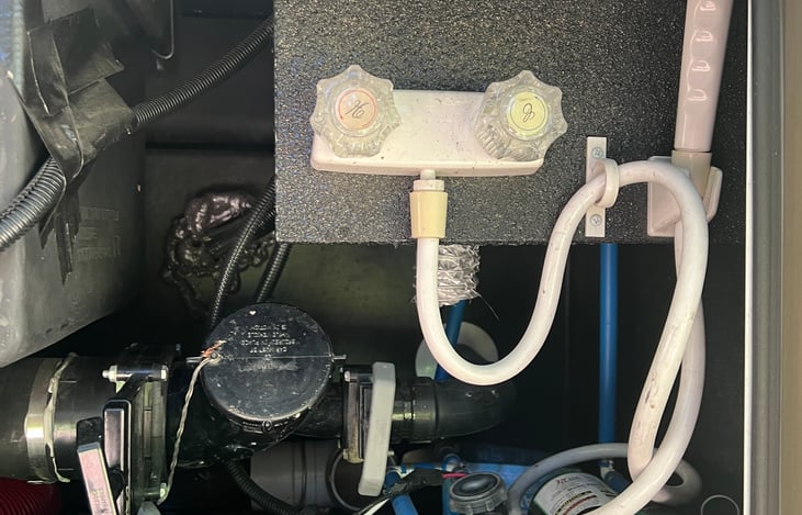 Outdoor shower.  Black/gray tanks drain pipe and control levers.