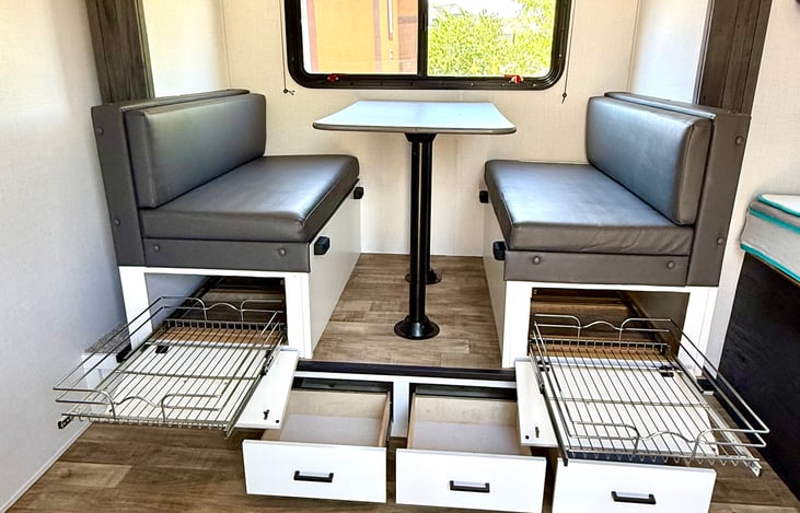 Five upgraded pull-out drawers under the dinette for organized storage of snacks, gear, and camping essentials.
