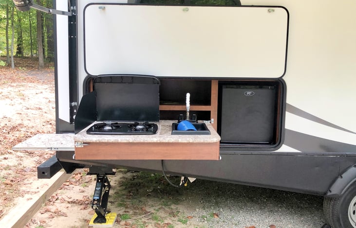 Outdoor Kitchen - Propane stove, sink, and fridge. Has storage above with electrical outlet