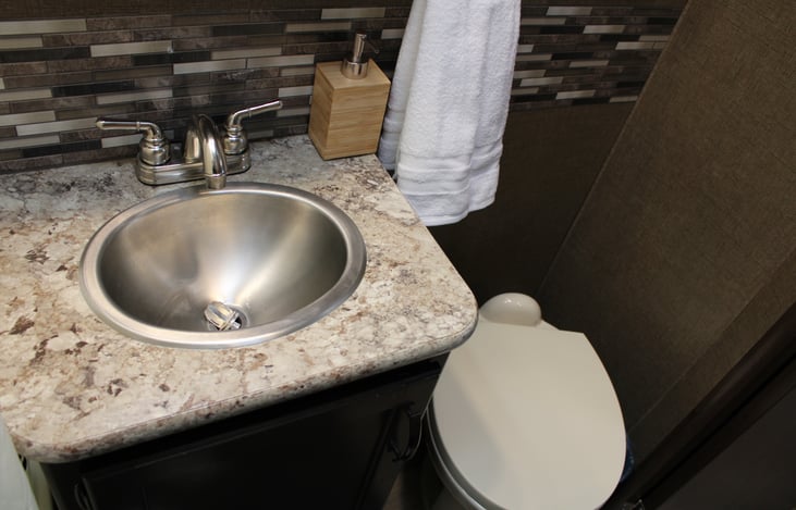 Stainless steel wash sink, and flushable foot pedal toilet. Toilet paper and santipods are  provided.