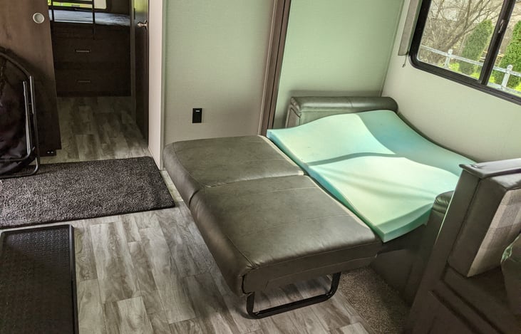 Memory foam mattress pad that levels the bed out, it's stored under the couch.