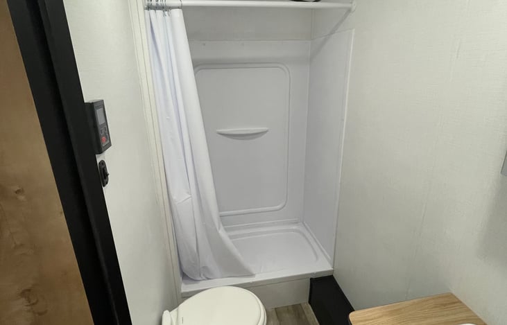 bathroom with shower, sink and porcelain toilet. Propane tankless water heater.