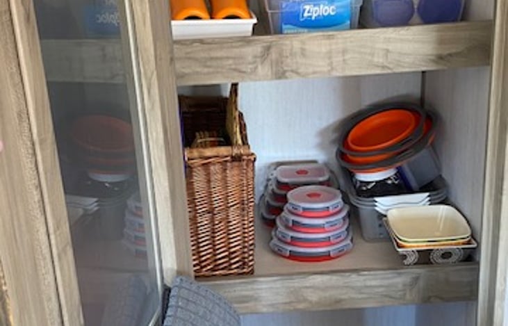 Pantry with bowls, plates, ziploc bags and collapsible containers.