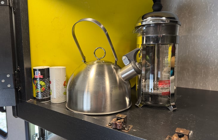 Cutting boards, salt & pepper, tea kettle and a french press coffee maker.