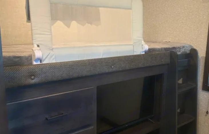 Bunk over drawers and a tv with a safety feature.