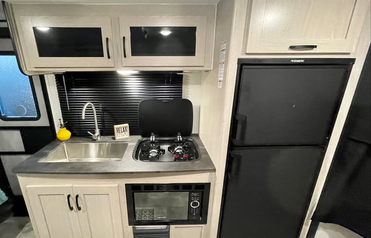 Your full-service kitchen with a two-burner range, microwave, sink, coffee pot, toaster, pots, pans, and cooking utensils, plus a huge fridge is ready for you!
