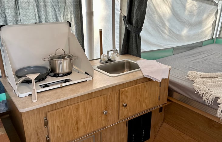 2 Burner stove & sink with storage cabinets.