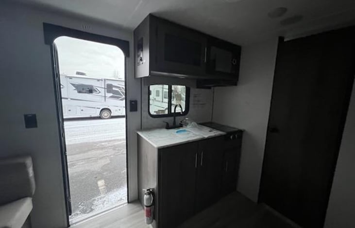 Kitchen sink, cupboards and door to bathroom