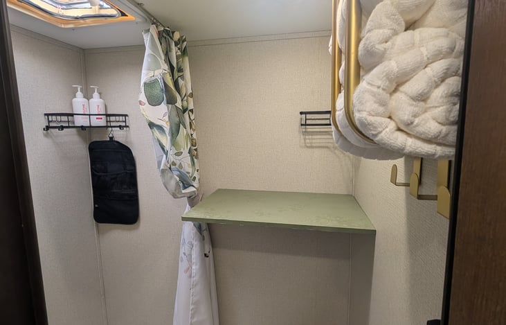 Bathroom features convenient fold down shelf, shower, towels, toiletry racks Shampoo and conditioner provided.