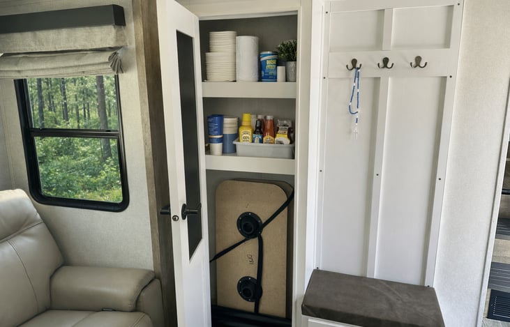 Interior pantry and entry storage cabinet with shelving and coat hooks. Ideal for snacks, paper goods, and organizing camping essentials.