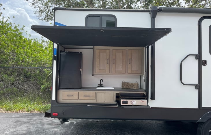 Outdoor kitchen with fridge, sink, cooktop, and storage.