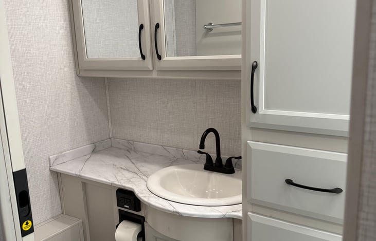 Full bathroom has toilet, sink, shower and plenty of cabinet space with large mirror.