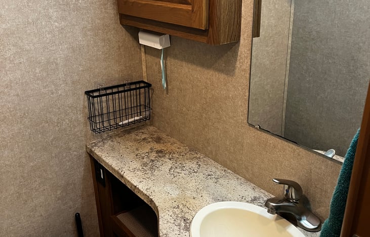 Spacious bathroom counter and porcelain toilet with 2 cupboards for toiletry storage.