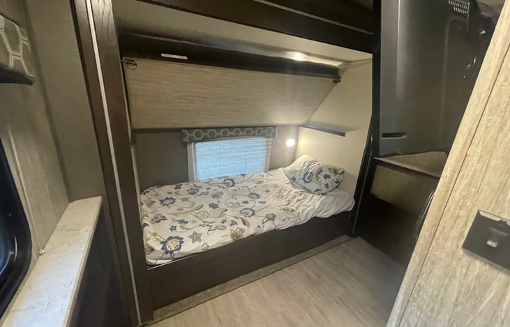 Bunk room with full privacy door, wall mounted TV and private half bathroom.