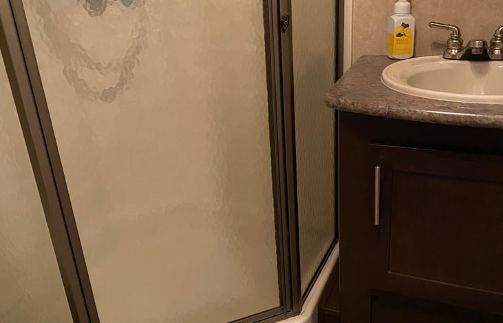 Full bath with corner shower and flushable potty.