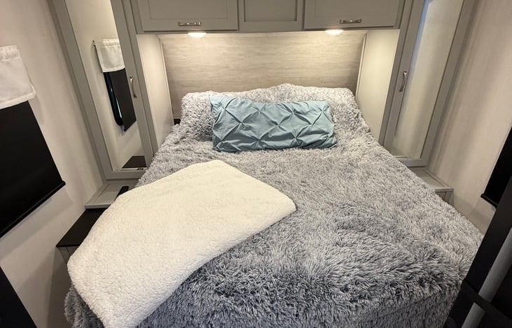 Master bedroom with cozy Queen.  TV in room. Closet space and storage under bed.  Even has cubbies with charging ports at head of bed on both sides.