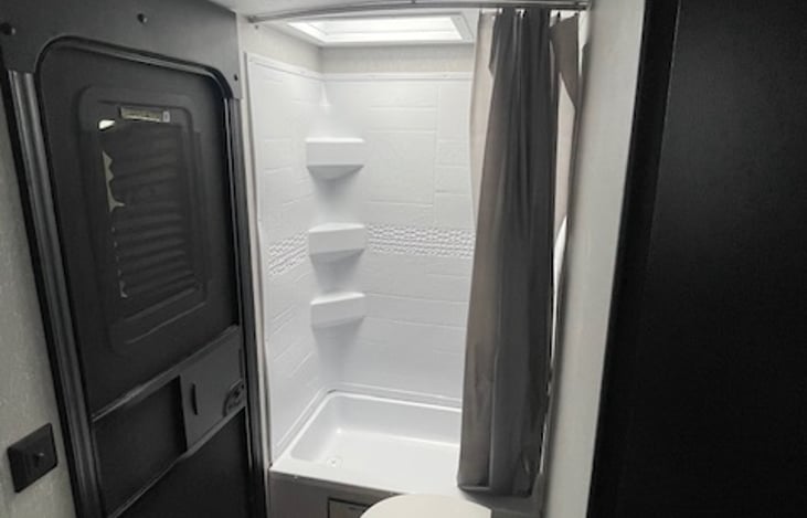 Spacious shower and bathroom with external exit door.