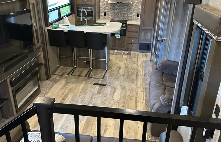 Large living area and a bar with three comfy barstools for dining.