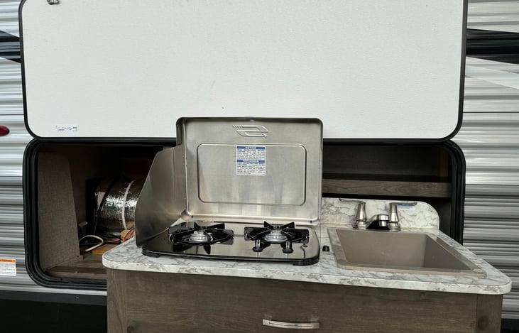 Outside Kitchen with  stove and sink and some storage.