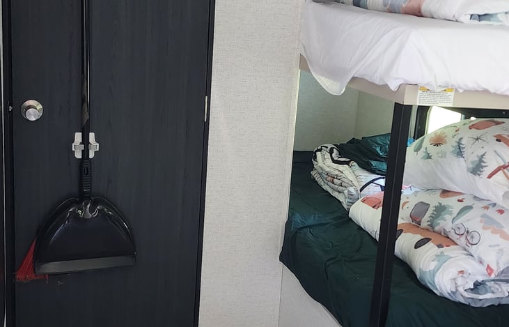 Broom and dust pan on back of bathroom door.