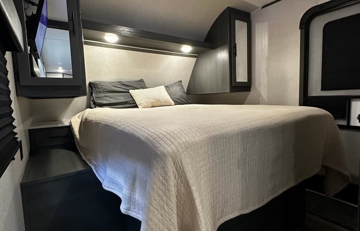 Over sized Queen mattress with sheets, blankets, and pillows.  Very comfortable.  Also has it's own exit door, and 2 overhead closets to hang clothes.