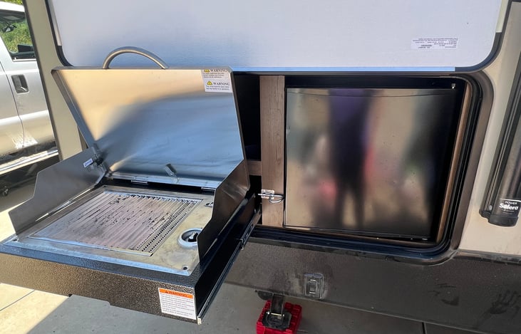 Outdoor kitchen with grill, grilling utensils and mini fridge