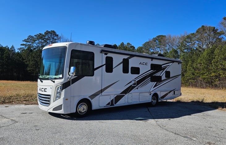 Experience luxury and versatility with the sleek left side of the 2024 Thor A.C.E. 32B, featuring expansive storage compartments, bold graphics, and a modern design perfect for your next adventure.