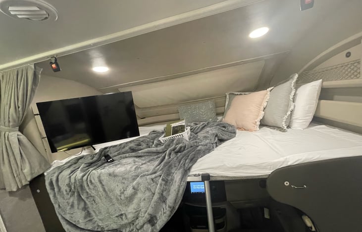 Over-cab bunk with ladder and TV, usb charger and wall switch.