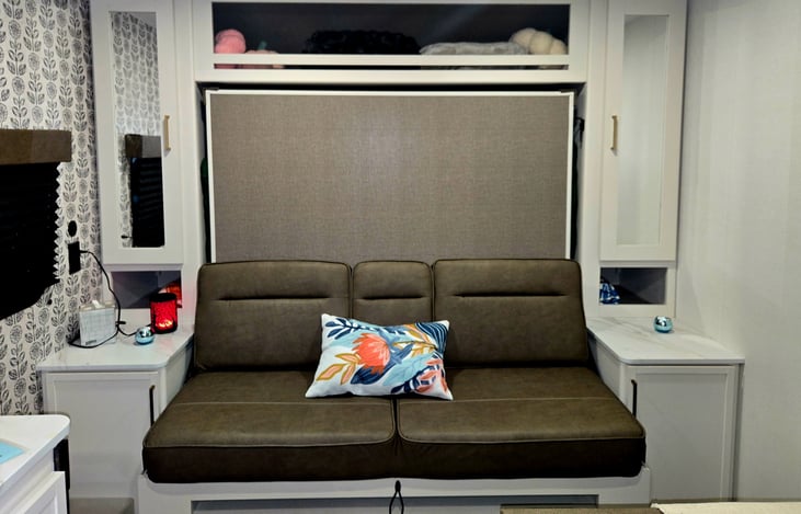 Couch area that folds down to Queen size bed. Storage on both sides, tall cabinets has place to hang clothes on one side and 3 shelves on other. Open storage on both sides and above.