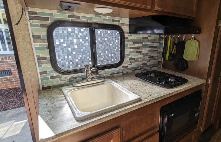 Kitchen has a large sink with upgraded pull-out sprayer faucet, a 2-burner propane stove, and a microwave-convection oven.