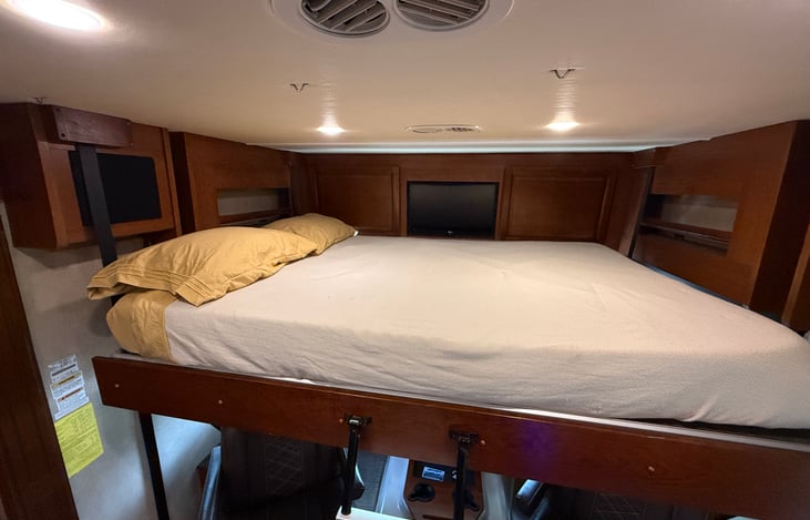 Drop down full bed has shelves and a TV