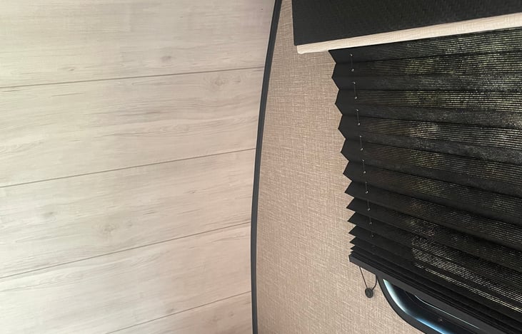 Right corner of queen bed and window with shades